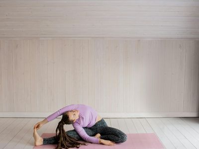 Legs stretching on a dark mat in a studio